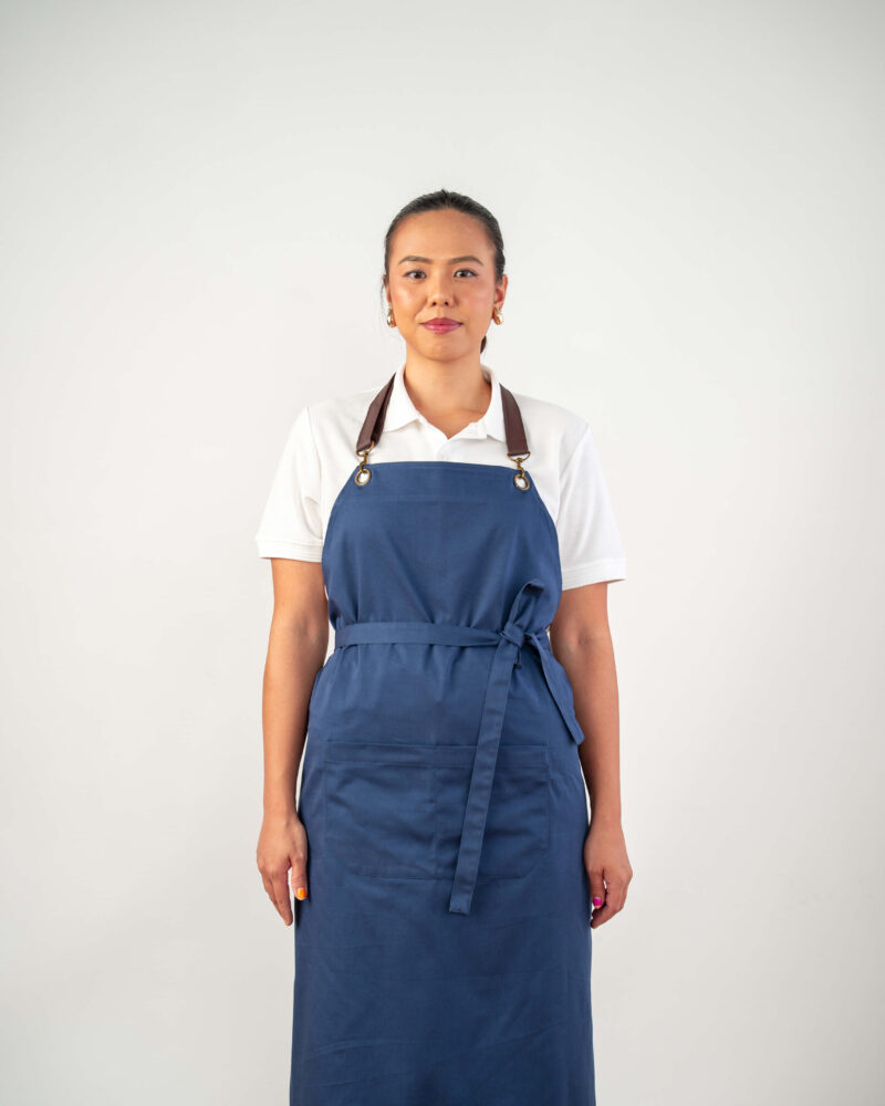 blue cotton bib apron, brown leather straps + brass clips